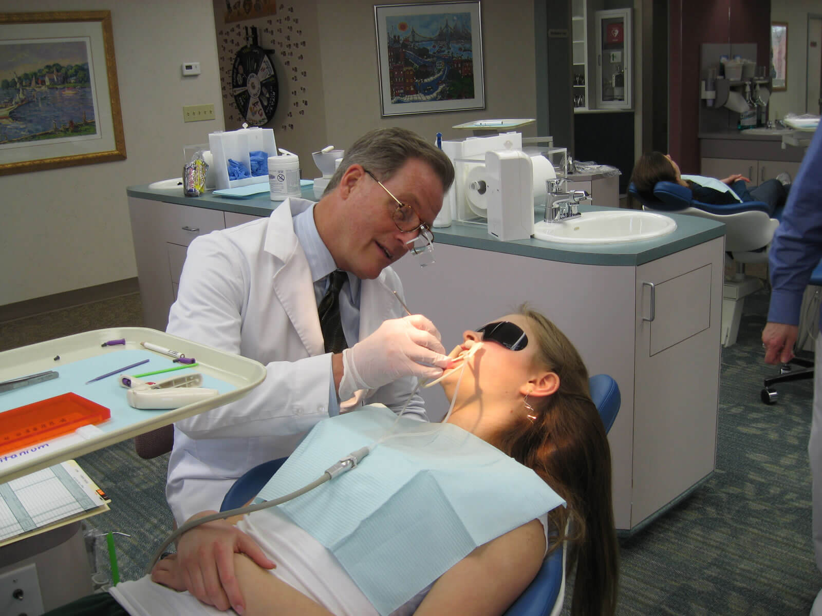 A patient is reclined in an exam chair while Dr. Gregg Frey carefully inspects her braces.