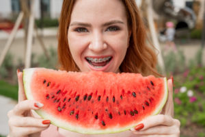 A girl with braces holds up a watermelon slice