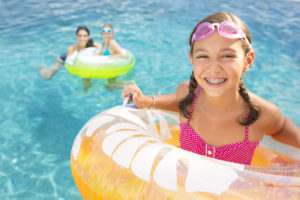 A girl with braces smiles while in a pool in a tube